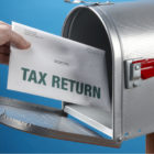 hand putting tax returns in mailbox